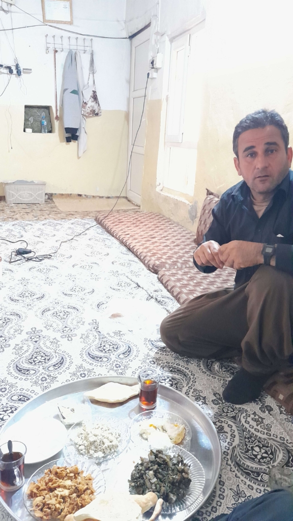 Auf dem Boden sitzend wird irakisches Essen auf einem Tablett Serviert.