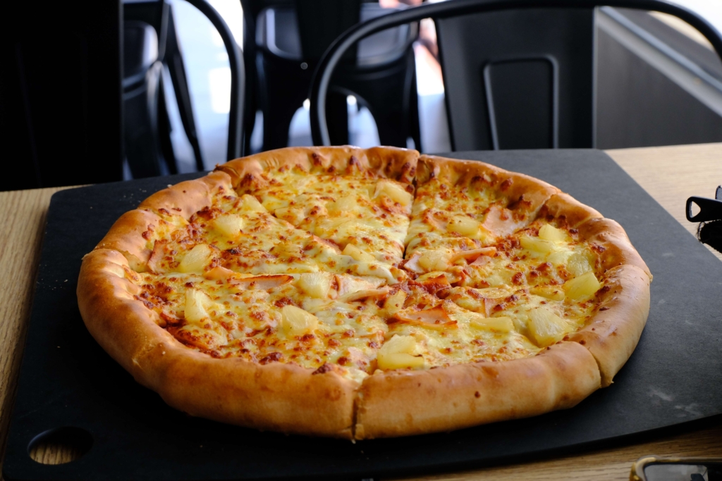 Eine Nahaufnahme einer Hawaiipizza (Schinken und Ananas). Ein kontroverses kulinarisches Thema.