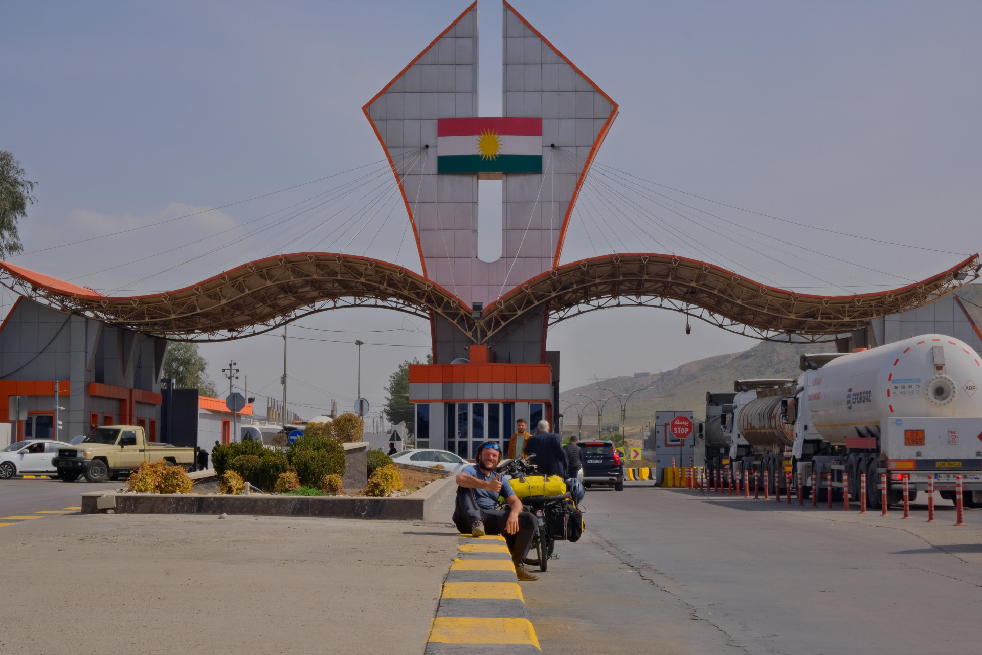 Ich sitze mit meinem Rad vor dem irakischen Grenzübergang; ein geschwungenes Dach überspannt die Straße, darüber thront die Flagge Kurdistans.