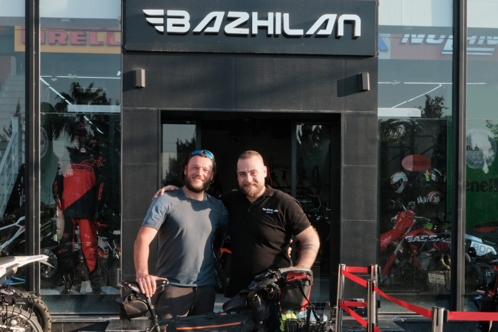 Ich stehe zusammen mit dem Besitzer vor einem Motorrad- und Fahrradgeschäft in Erbil.