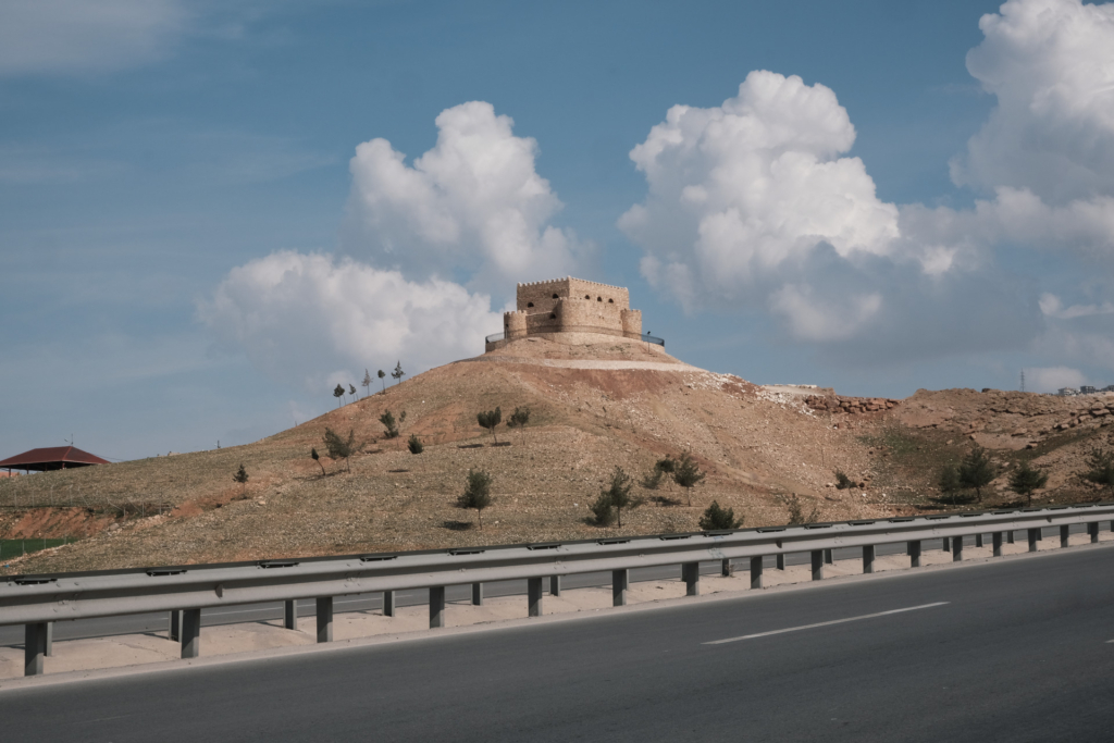 Ein Sandfarbenes Fort auf einem Berg neben der Straße
