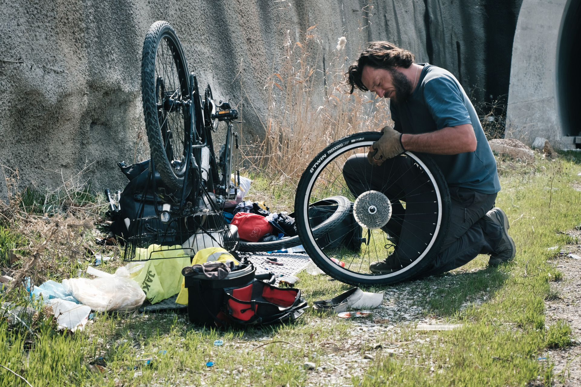 Ich knie am Straßenrand neben meinem kopfüber liegenden Fahrrad und repariere es und die Taschen.