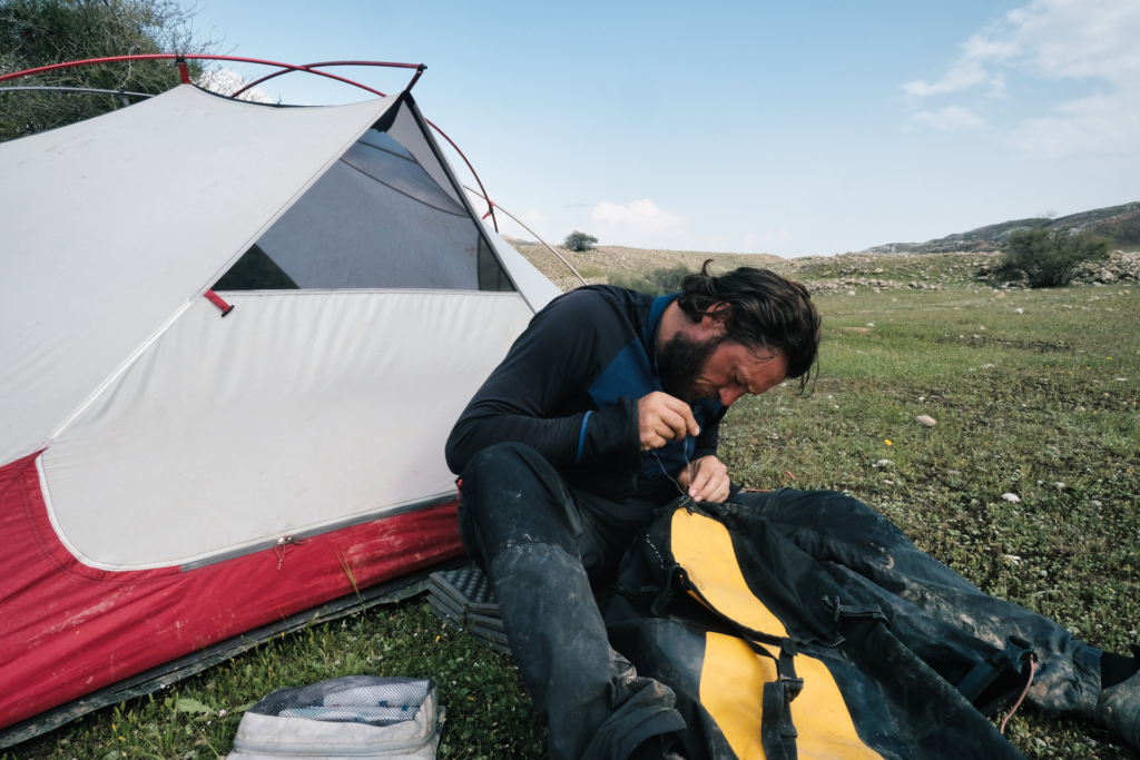 Ich sitze vor dem Zelt und nähe meine Fahrradtasche mit Zahnseide