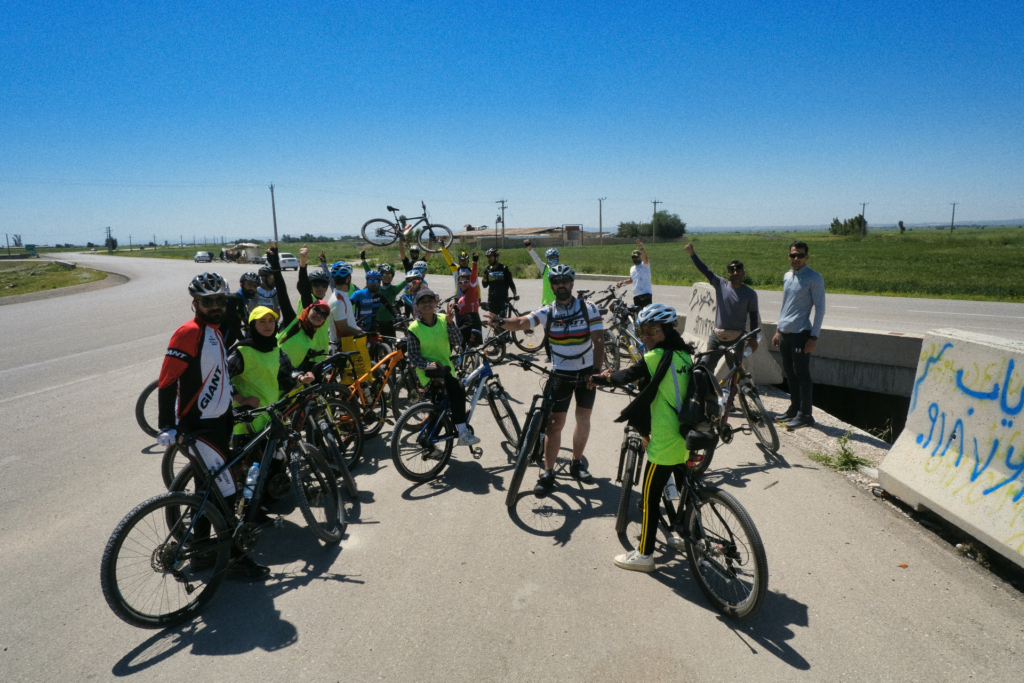 Eine Gruppe von 22 Fahrradfahrern begrüßt mich mit gehobenen Händen. Einer von ihnen hat sein Fahrrad in die Luft gehoben.