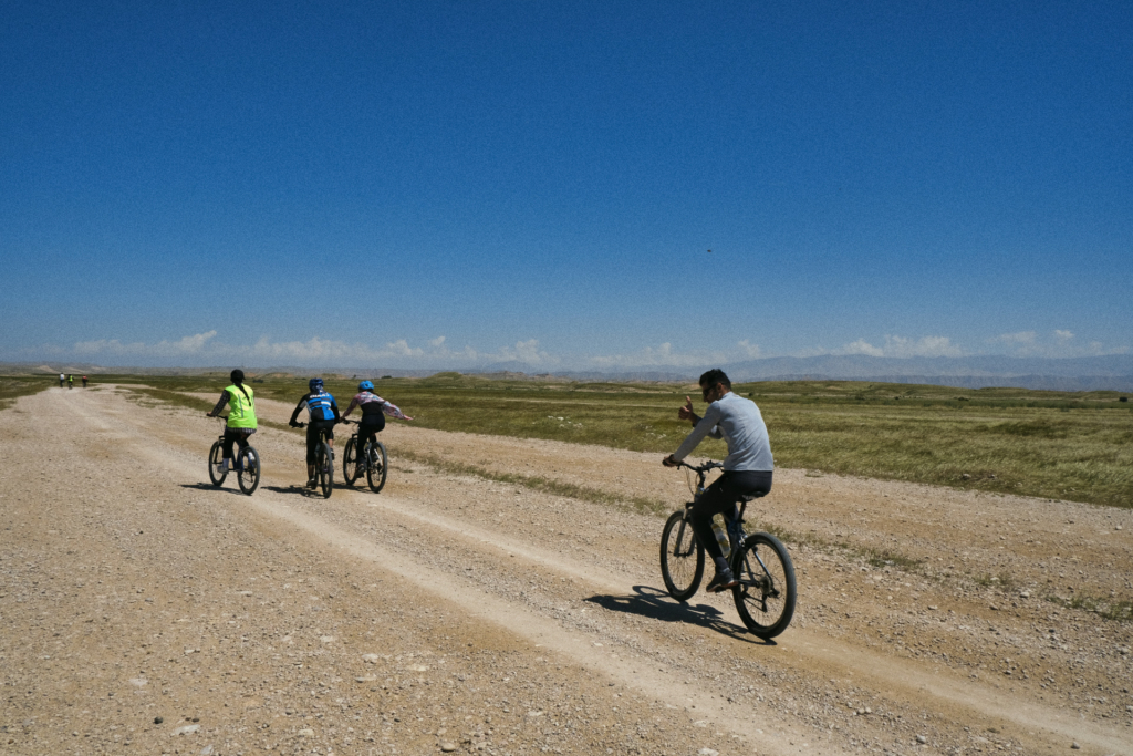 Über Kieswege an der flachen Steppe entlang fährt eine Gruppe Fahrradfahrer