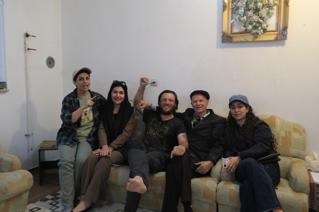 Ich sitze auf einem Sofa, umgeben von meinen Gastgebern.