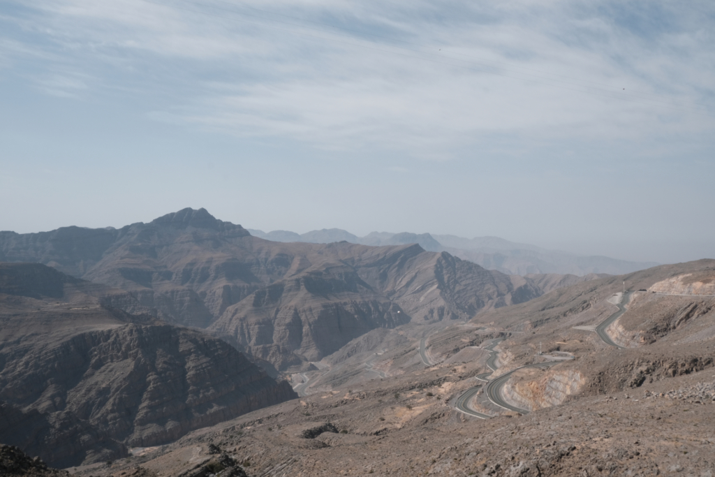 Wir stehen an einem Abgrund mit Blick auf ein Gebirge im Hintergrund. Unter uns sehen wir die unendlichen Serpentinen, die ich eben noch hochgefahren bin.