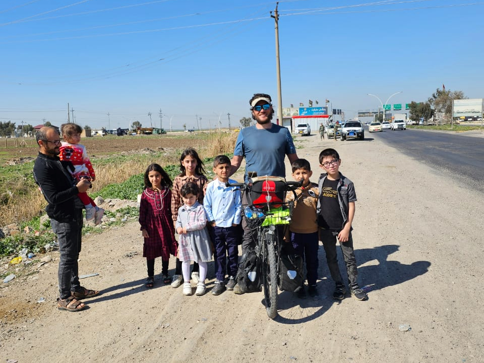 Ich sitze auf dem Fahrrad, umringt von sechs Kindern. Der Vater steht daneben und hält das siebte Kind auf dem Arm.